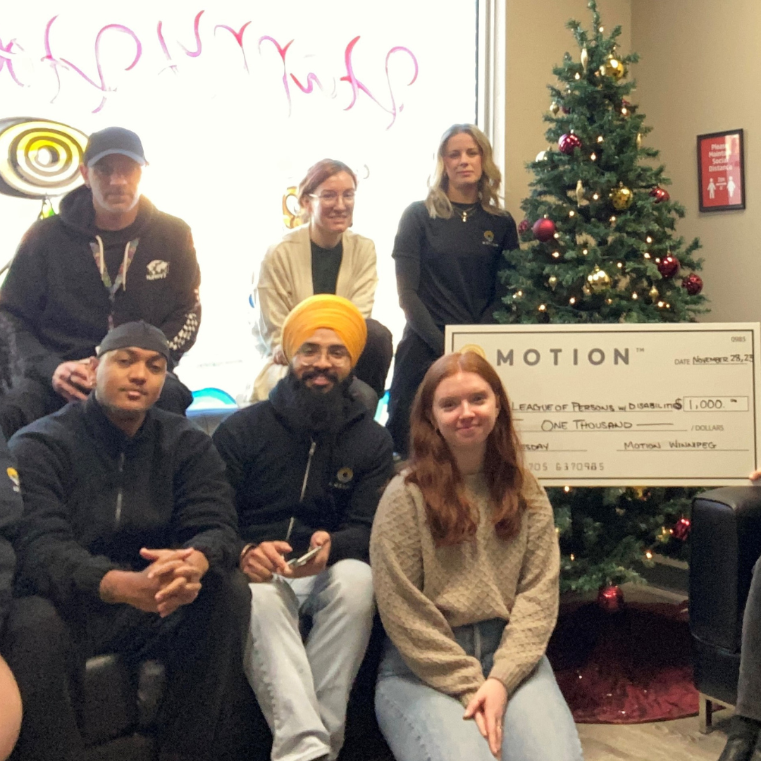 Motion Winnipeg team members holding a novelty cheque representing a donation to the Manitoba League of Persons with Disabilities