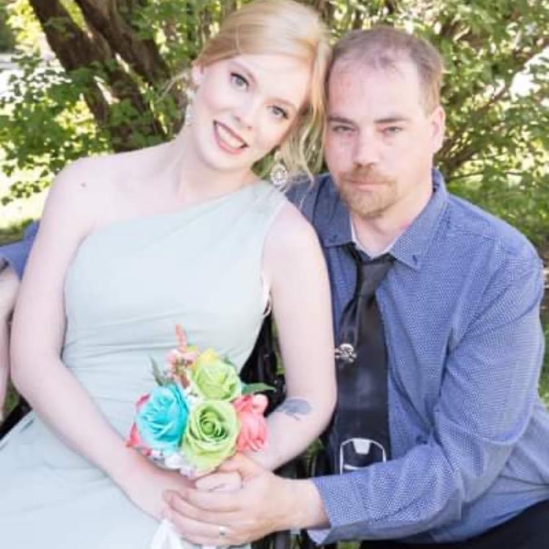 Amanda posing with her boyfriend at an event. She is holding a bouquet of flowers.